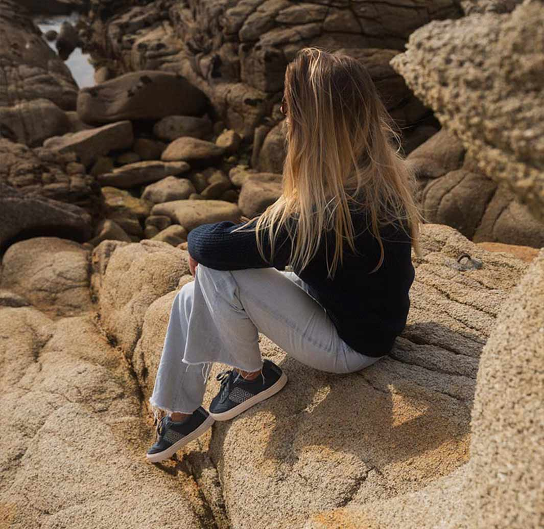 Woman With Black Sneakers Sitting On Rocks